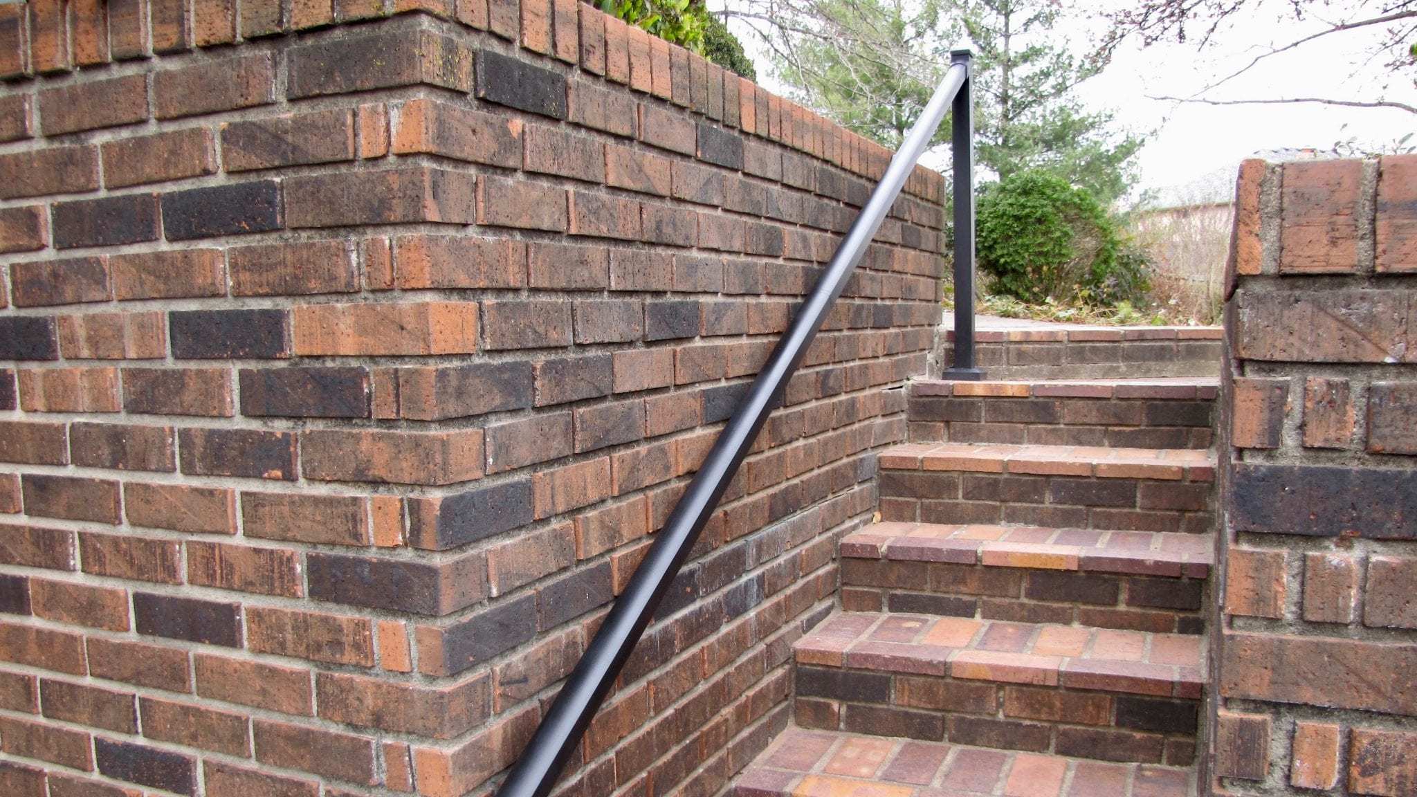 aluminum handrail on brick wall over brick stairs